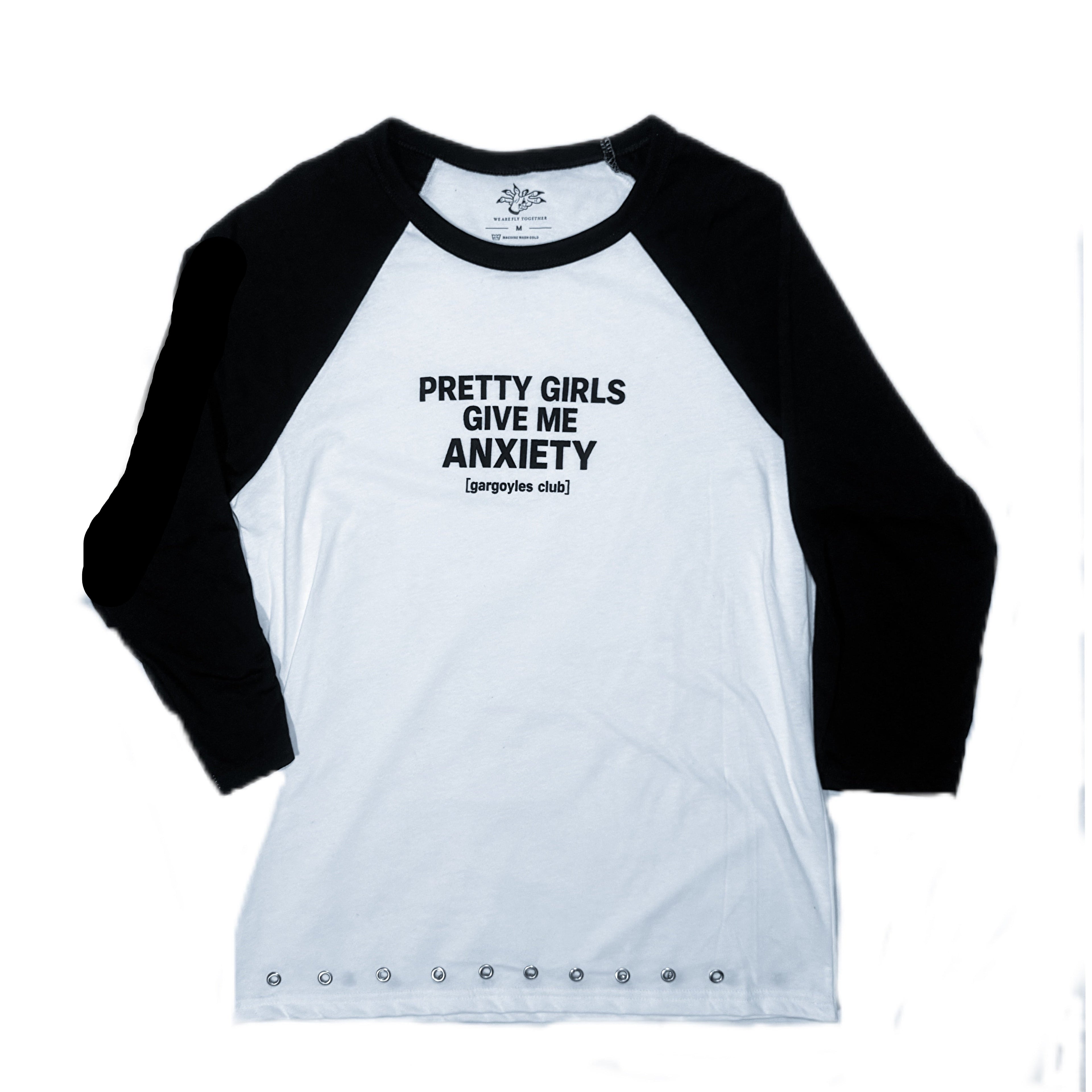 A 3/4 sleeve raglan baseball t-shirt with a white body and black sleeves, featuring the text 'PRETTY GIRLS GIVE ME ANXIETY' printed in black on the chest.